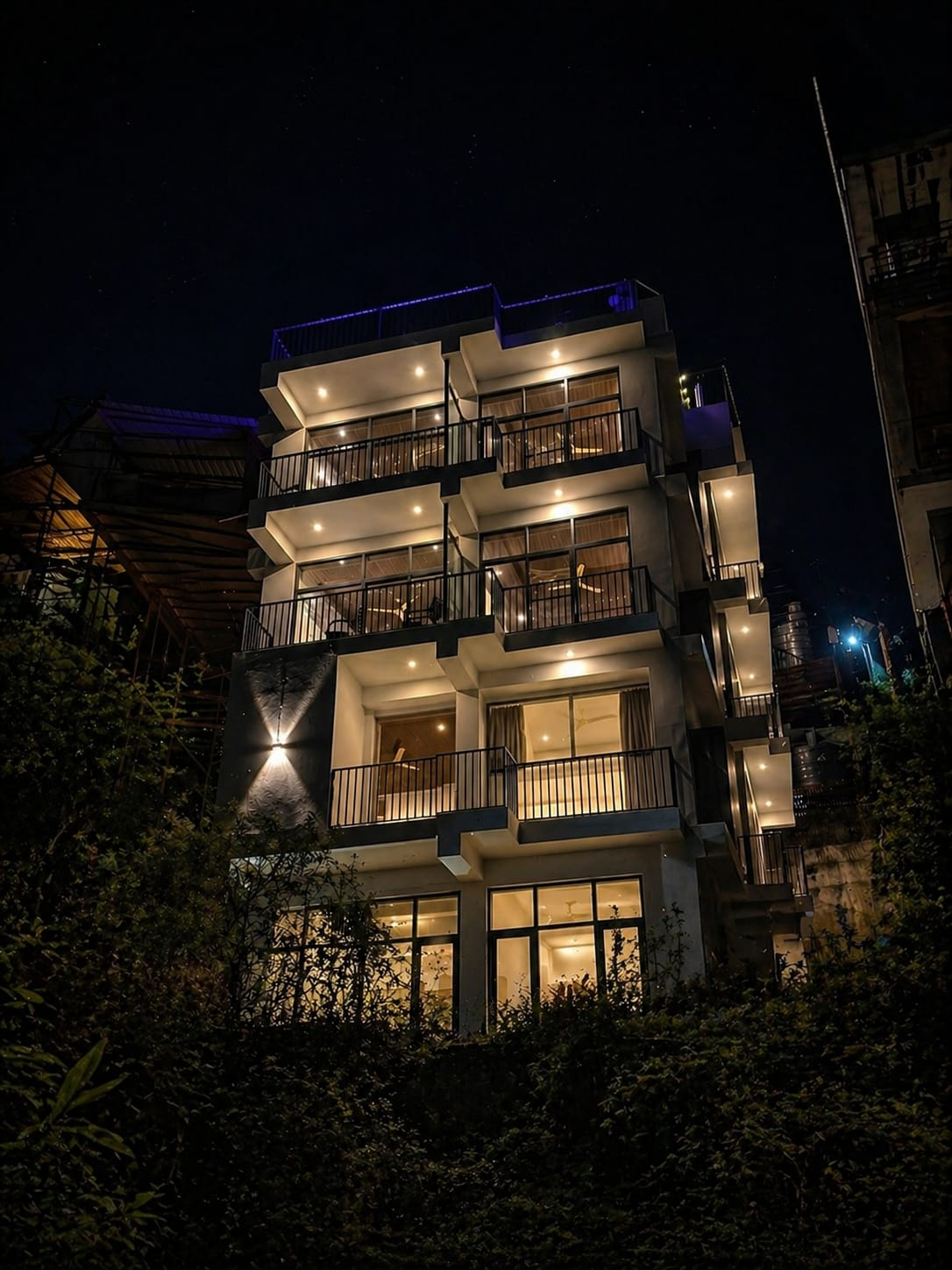 Shubh Inn building lit up at night with balconies